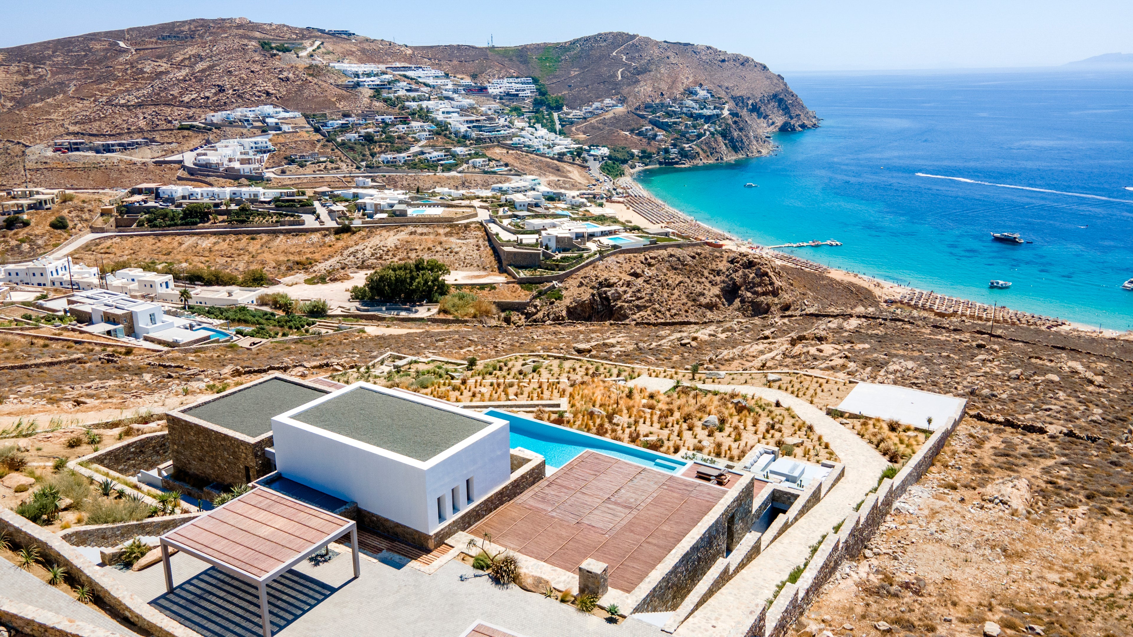 Modern villa with pool overlooking a coastal landscape and blue sea.