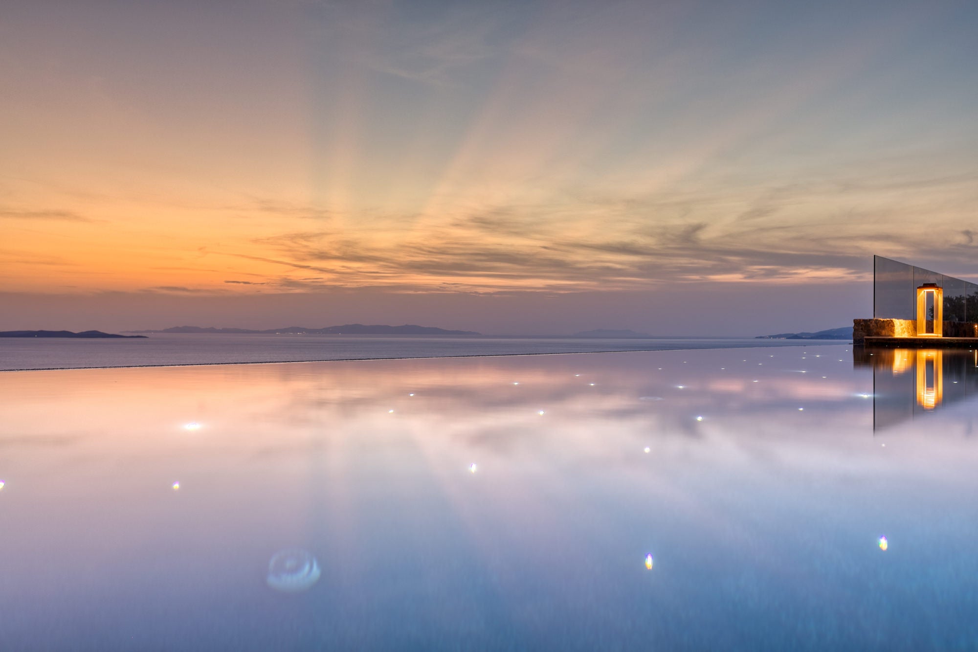 Reflective water surface with a building and colorful sky at sunset.