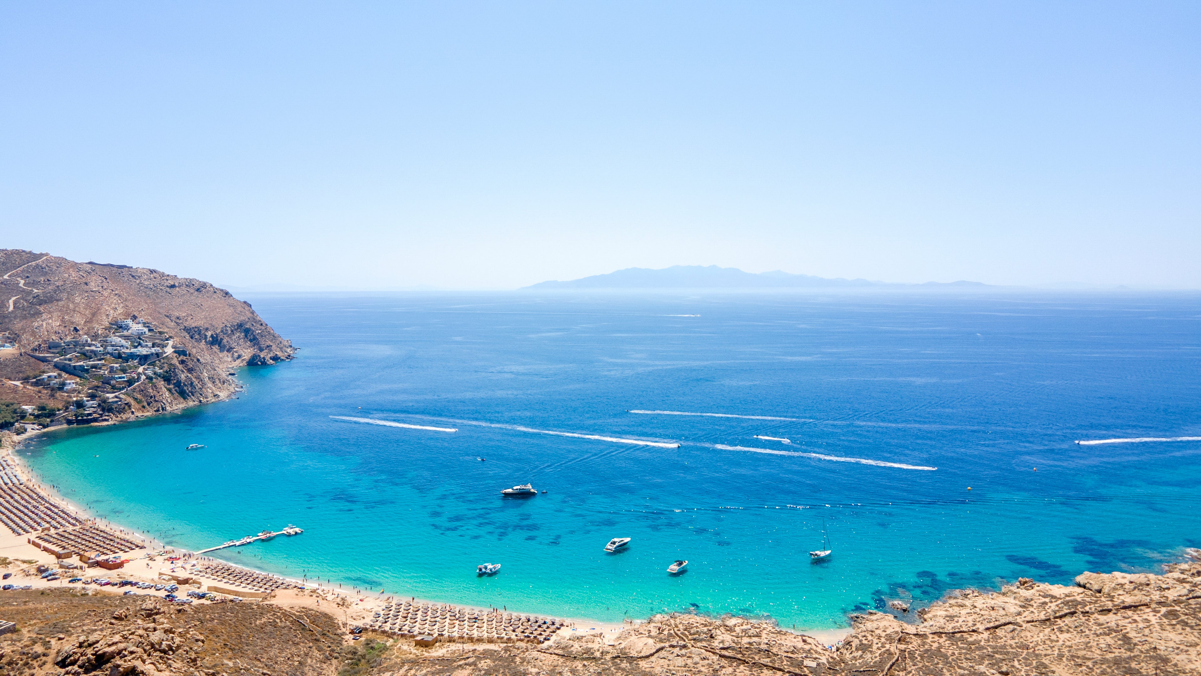 Coastal scene with clear blue water, boats, and a clear sky.