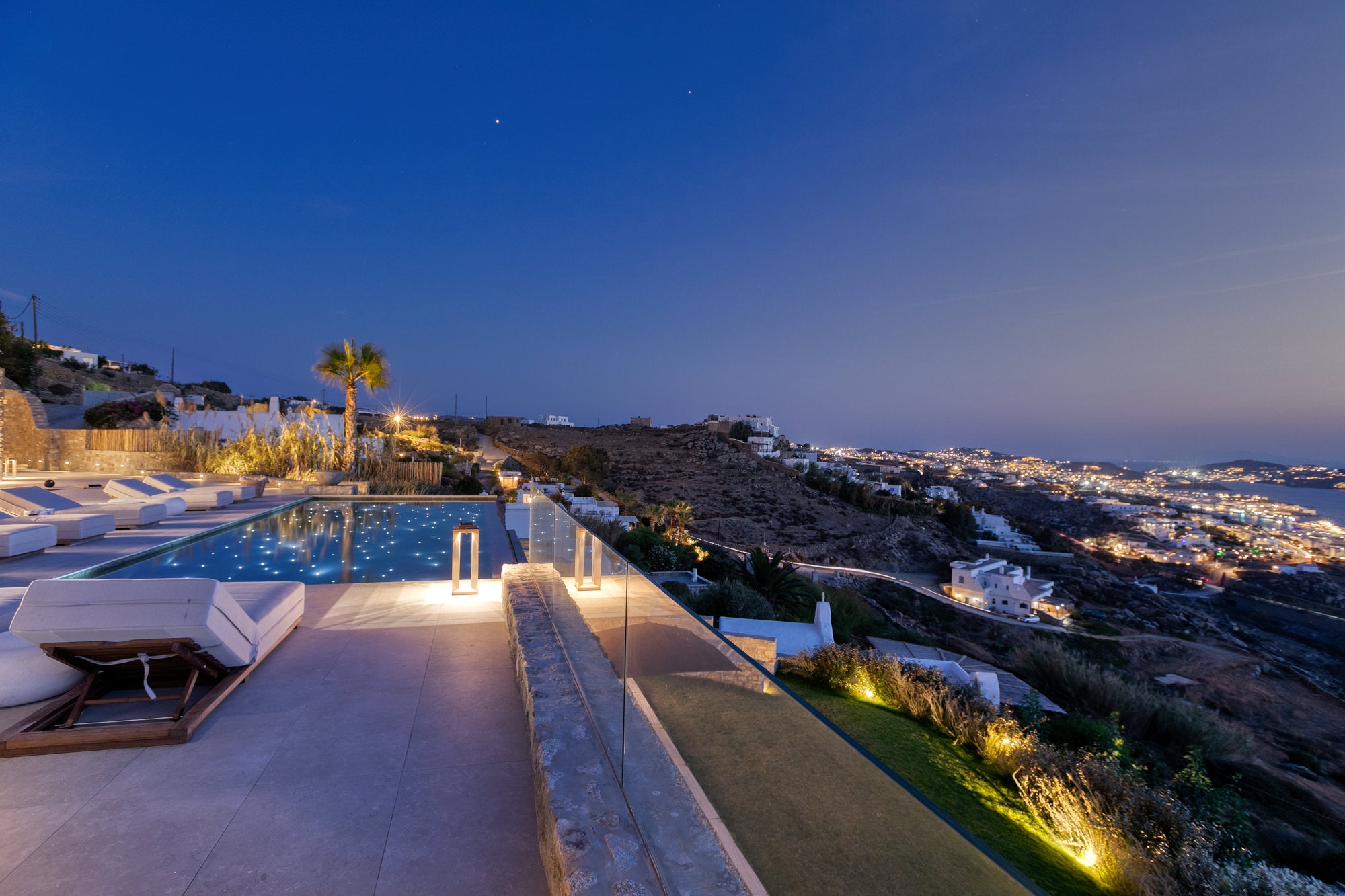 Luxury pool area with white chairs and a scenic view at night.