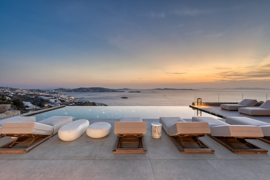 Modern outdoor seating area with a view of the ocean at sunset.
