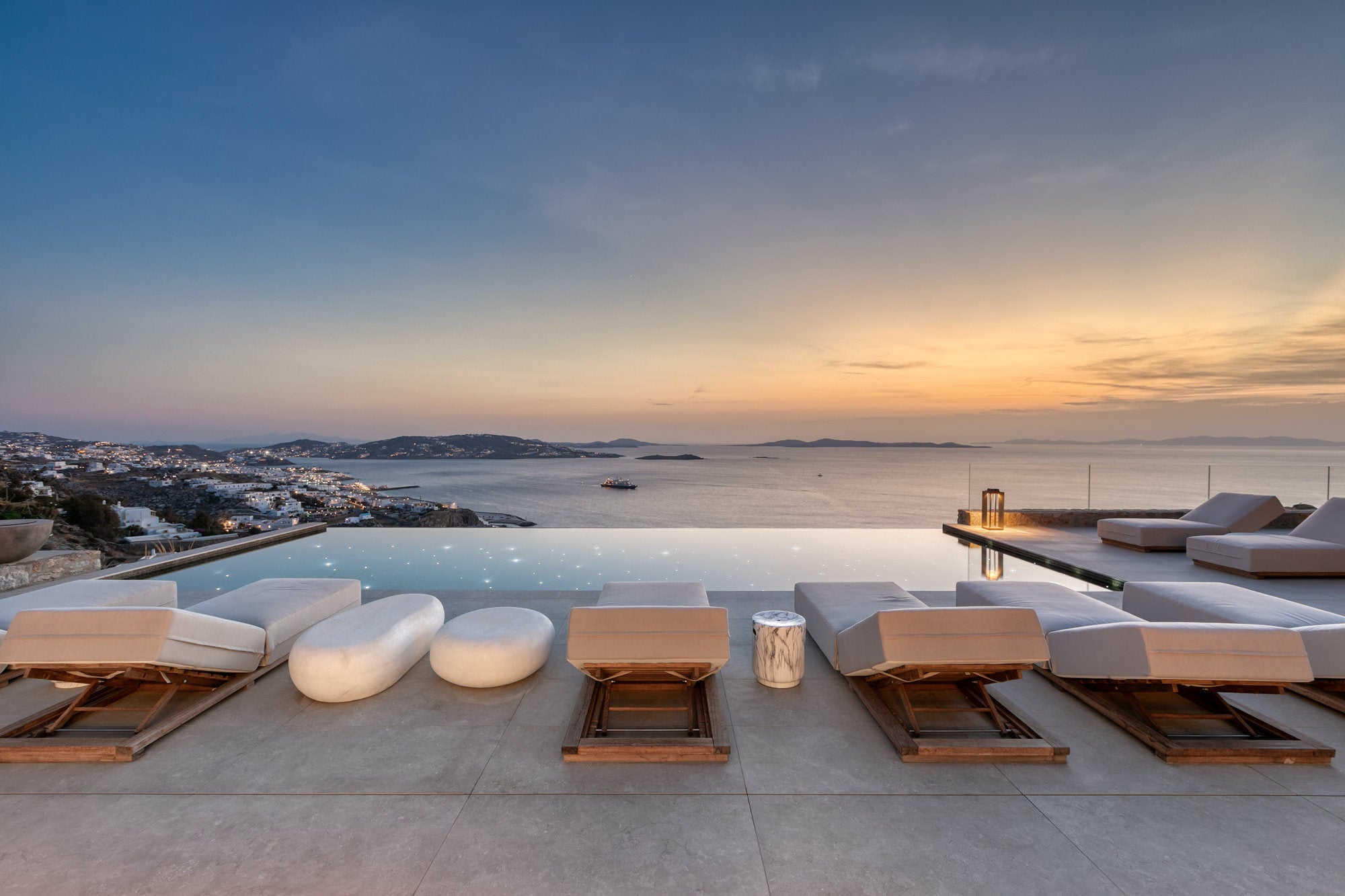 Modern outdoor seating area with a view of the ocean at sunset.