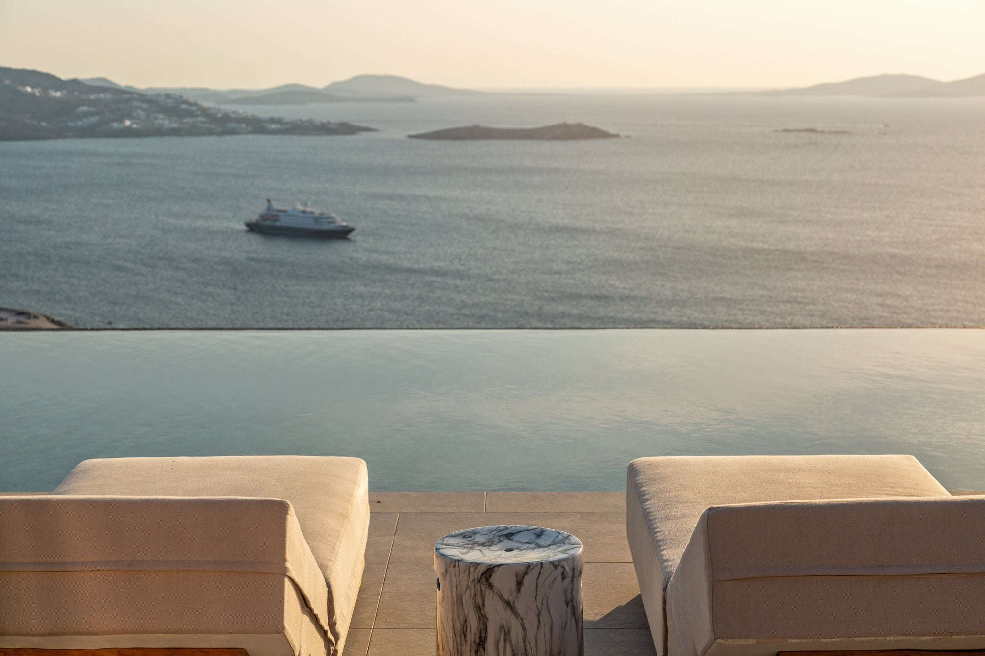 Beige outdoor furniture set with a view of the ocean and a ship in the distance.