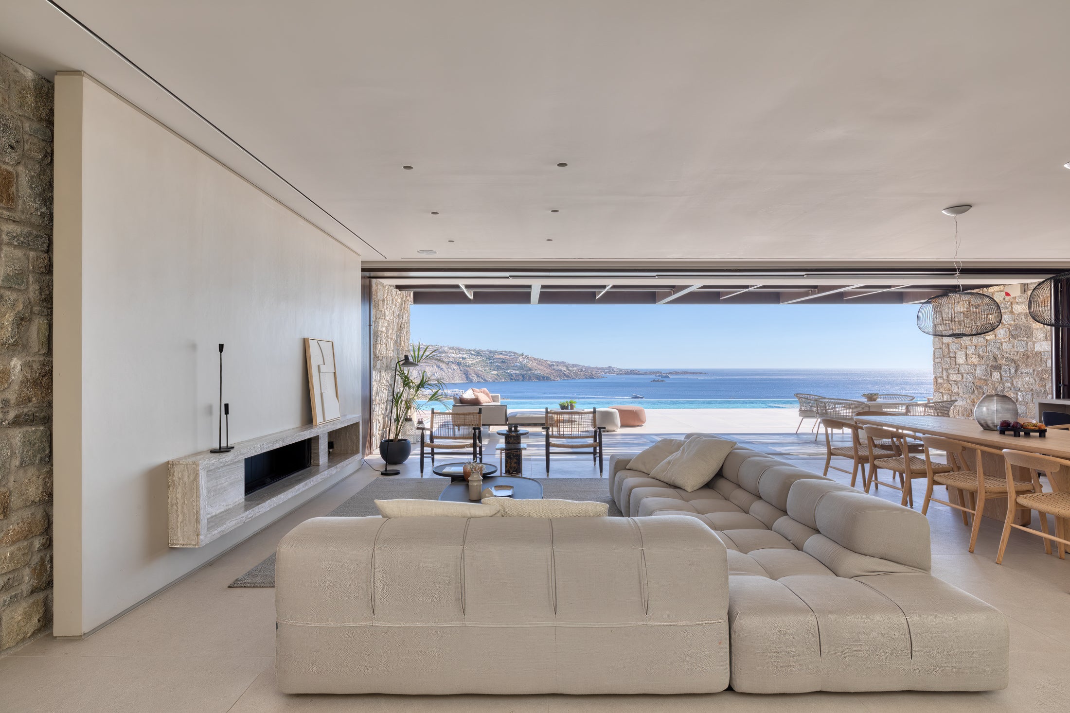 Modern living room with a large sectional sofa, fireplace, and view of the ocean.