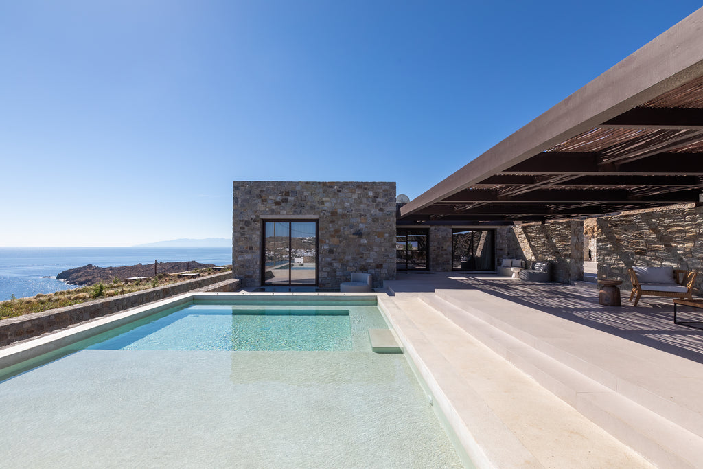 Modern house with a pool overlooking the ocean under a clear blue sky.