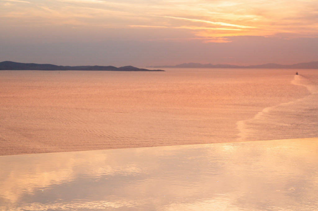Sunset over a calm body of water with a small island in the distance.