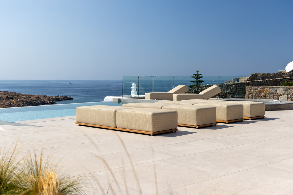 Beige outdoor furniture set by a pool with ocean view
