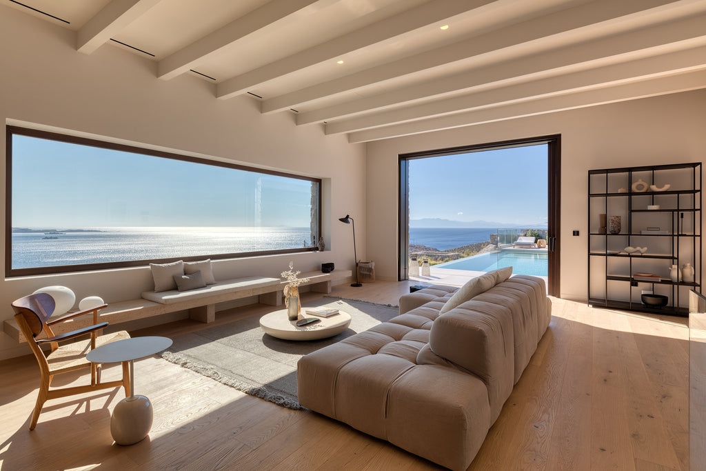 Modern living room with large windows overlooking a pool and ocean.