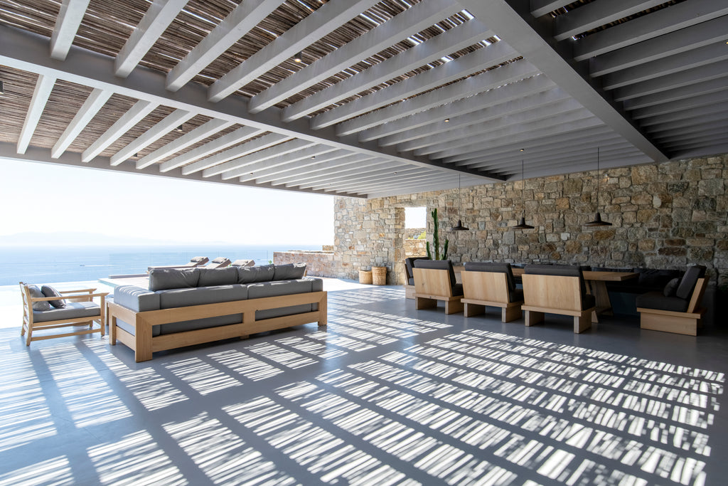 Outdoor patio area with wooden furniture and stone wall.