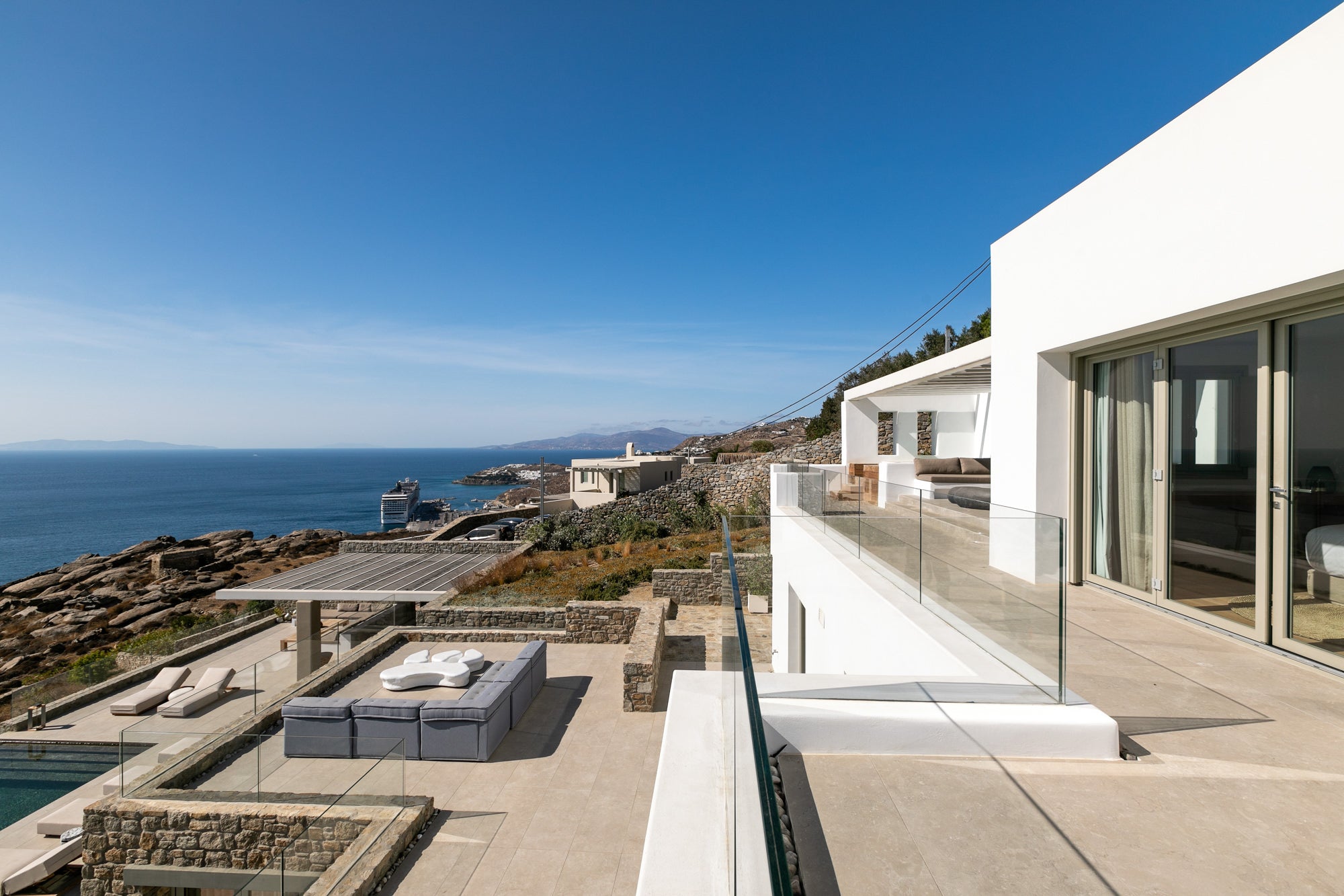 Modern house with a balcony overlooking the ocean and coastal landscape.