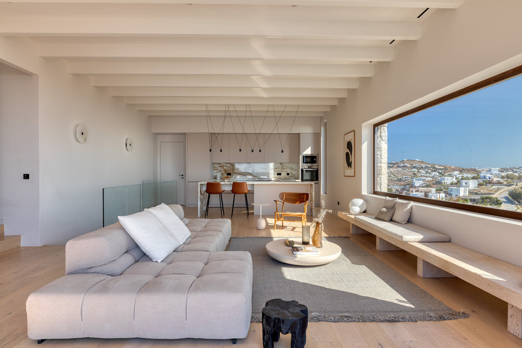 Modern living room with a large window view of a coastal town.