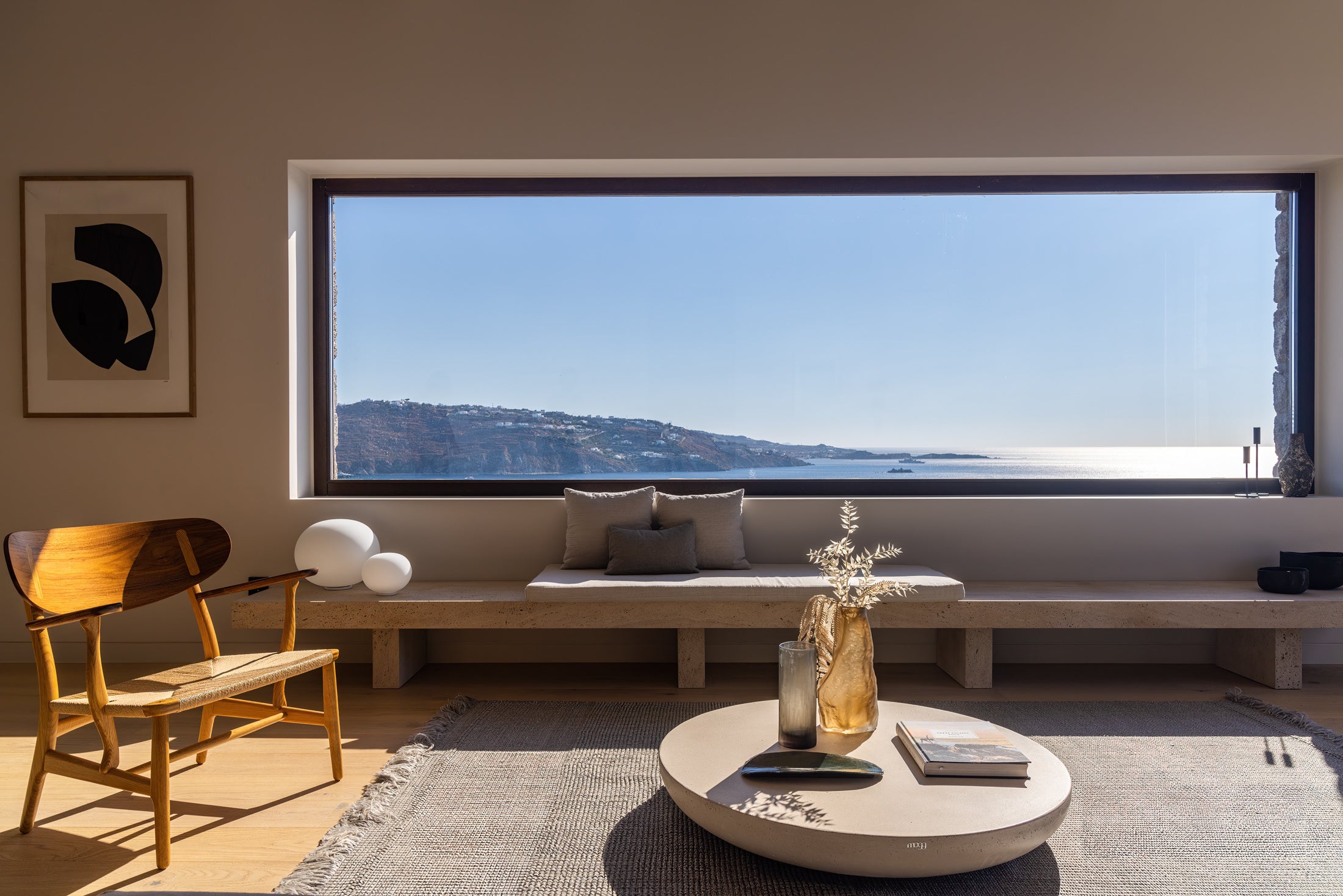 Modern living room with a large window view, wooden chair, and round coffee table.