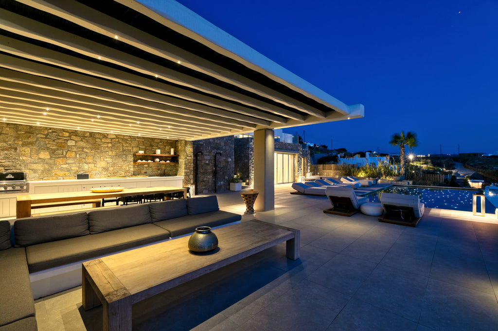 Modern outdoor patio with seating area and pool at night