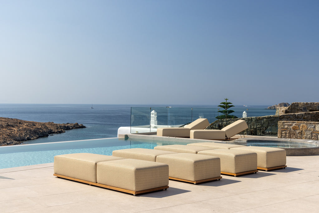 Beige outdoor furniture set by a pool with ocean view
