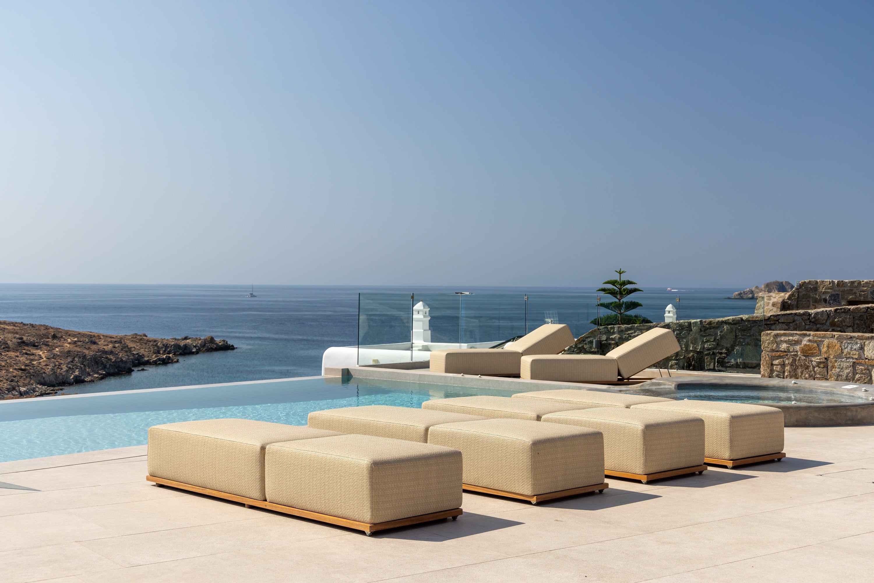 Beige outdoor furniture set by a pool with ocean view