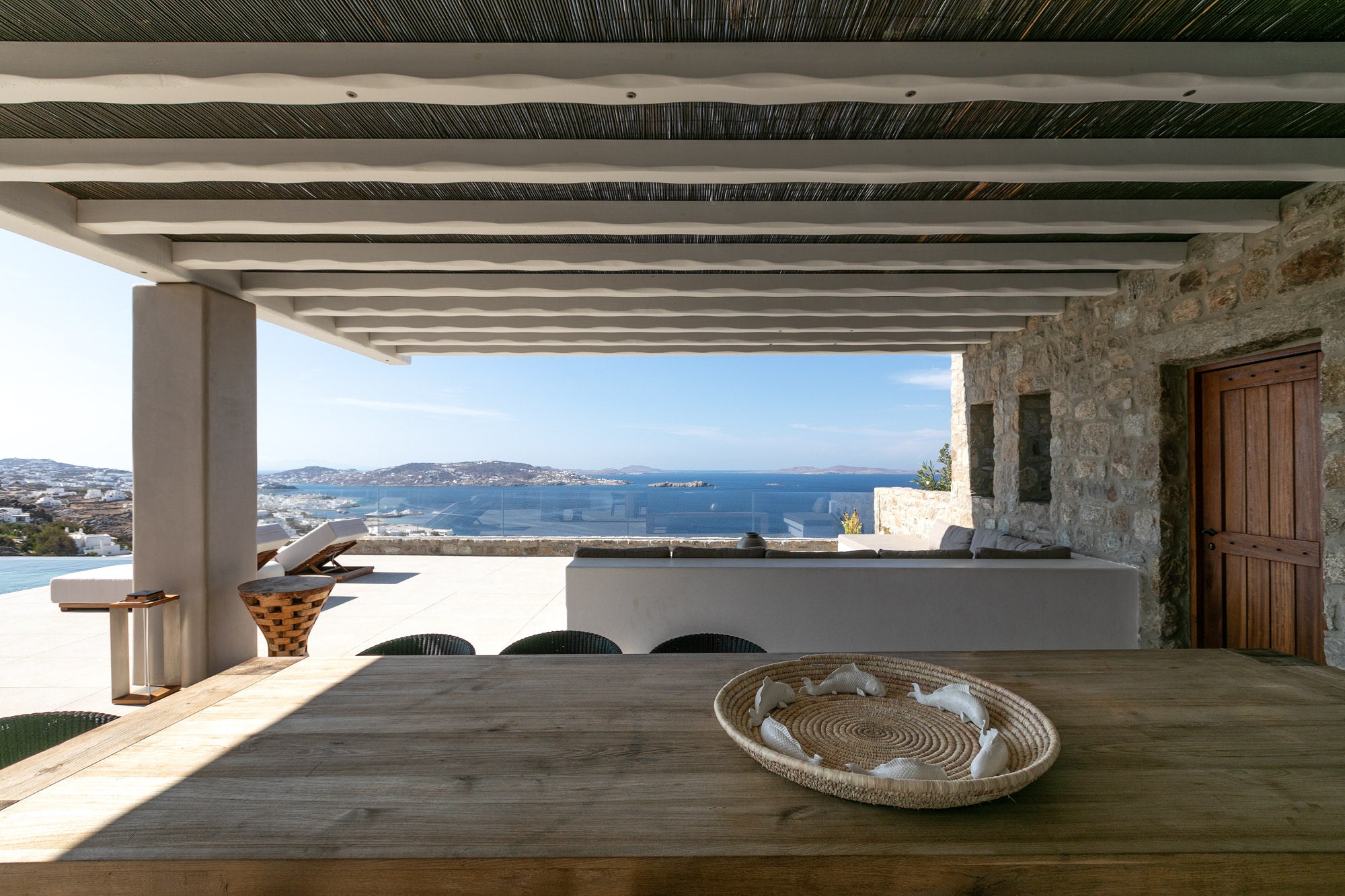Outdoor dining area with a view of the ocean from a stone building.