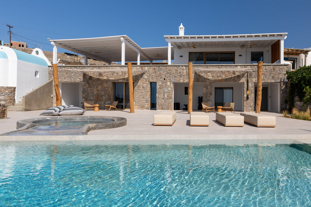 Luxury villa with pool and outdoor seating area under a clear blue sky.