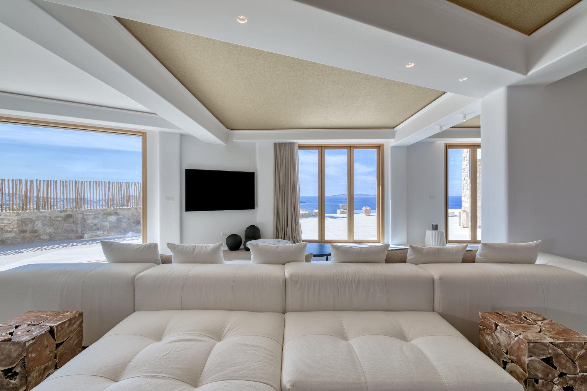 Modern living room with a large sectional sofa, TV, and scenic windows.