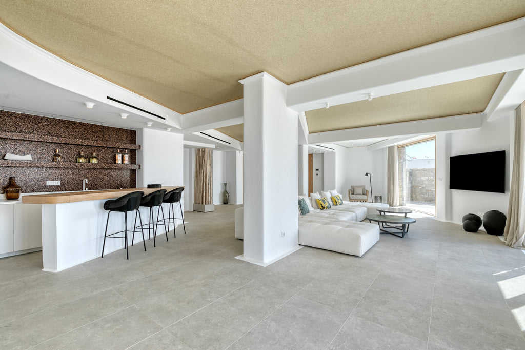 Modern living room with kitchen area featuring white furniture and neutral decor.
