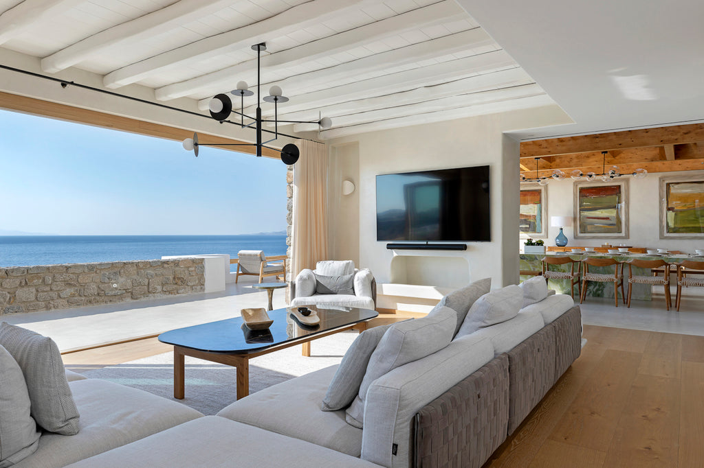Modern living room with ocean view, gray sofa, and TV.
