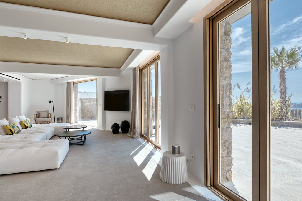 Modern living room with white furniture, large windows, and a view of the ocean.