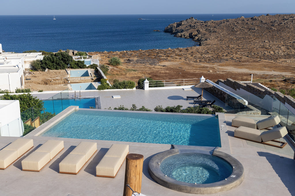 Outdoor pool area with ocean view and sun loungers on a sunny day.