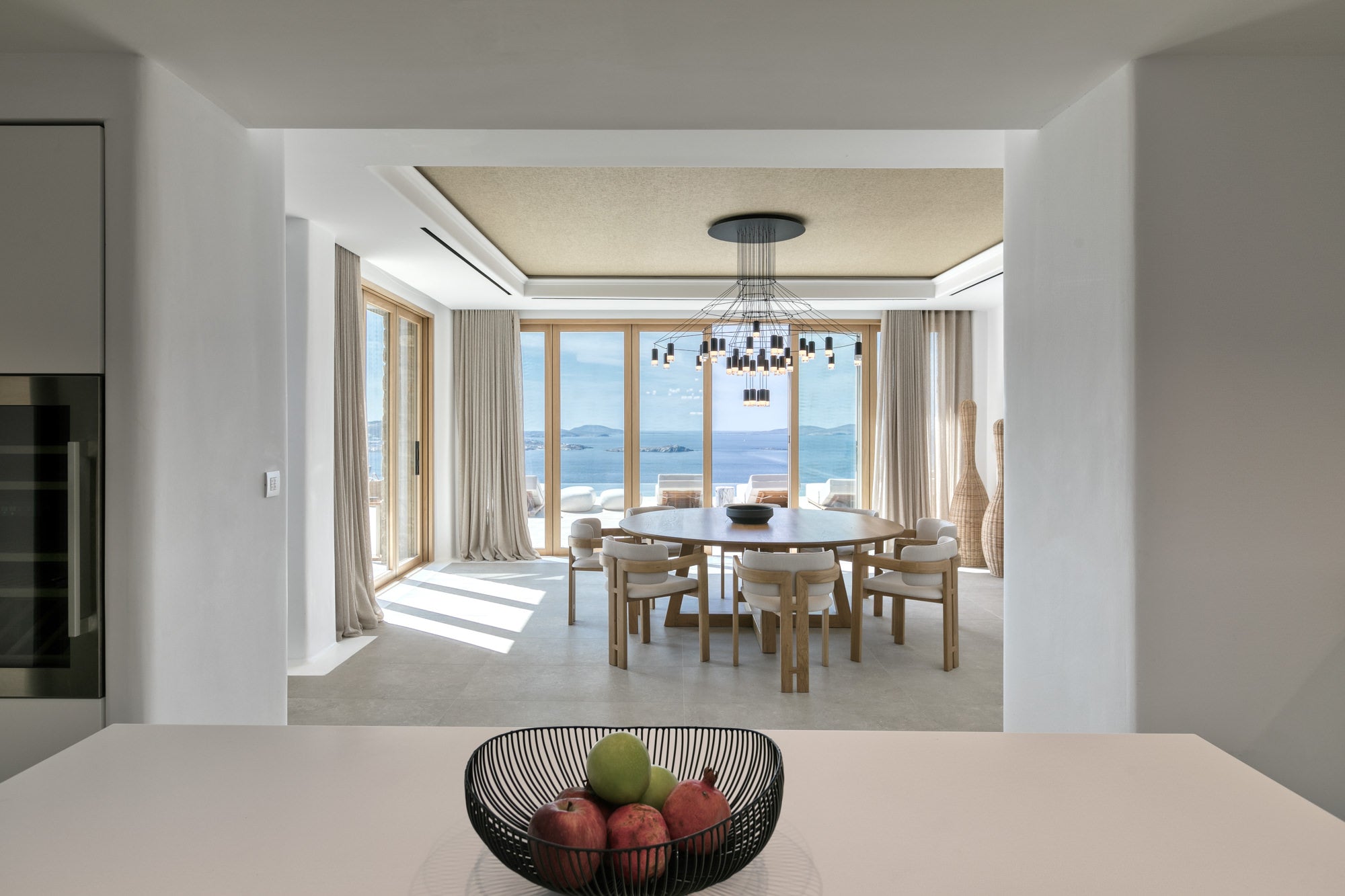 Modern kitchen with a view of a dining area and large windows.