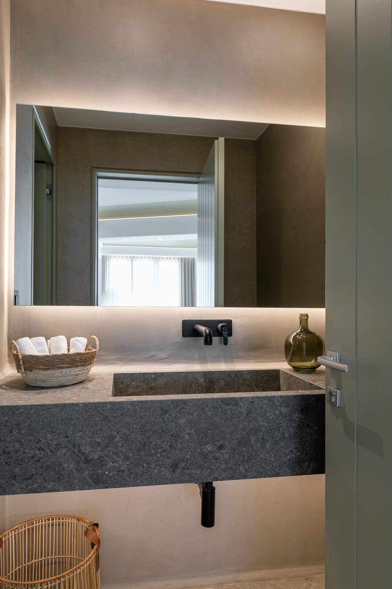 Bathroom vanity with a large mirror, sink, and decorative items.