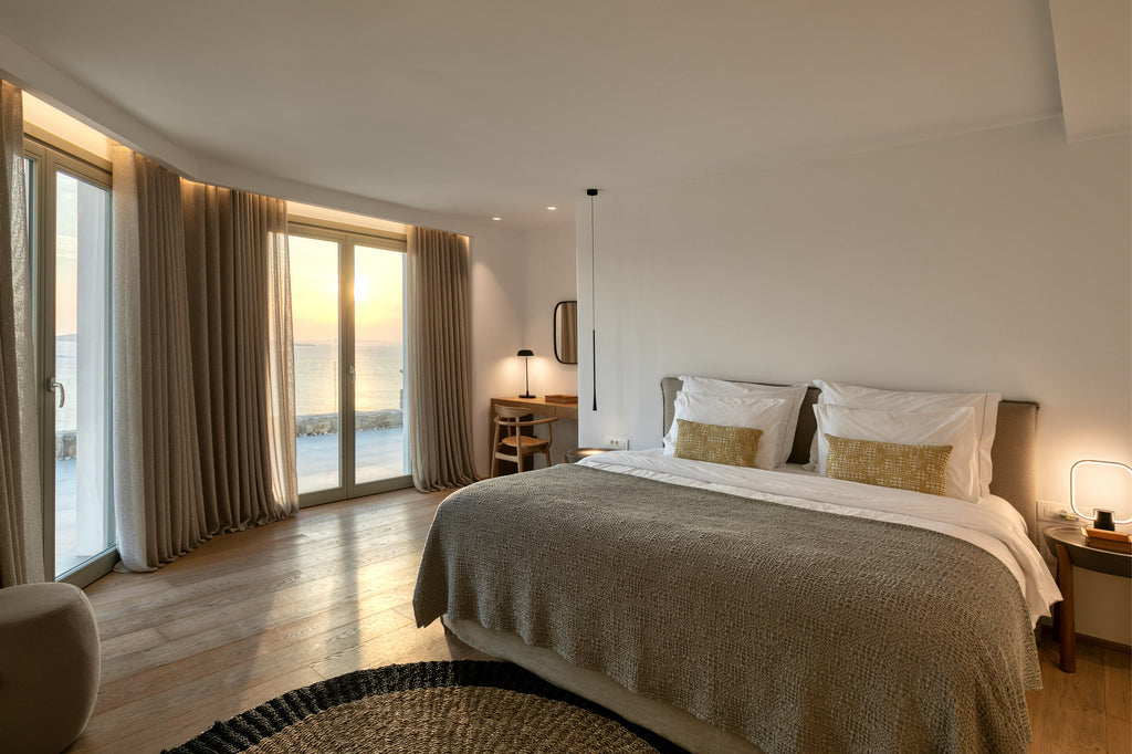 Modern bedroom with large windows, bed, and desk.