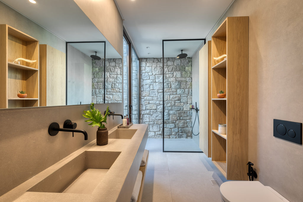 Modern bathroom with stone walls, wooden shelves, and a glass shower enclosure.
