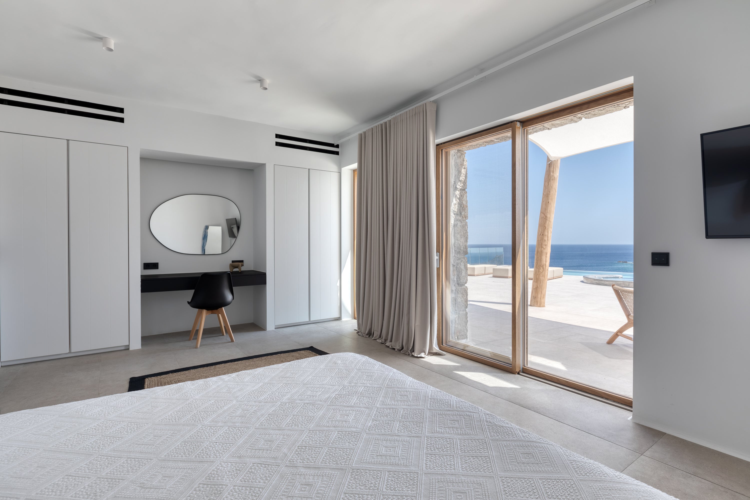 Modern bedroom with a large window overlooking the ocean.