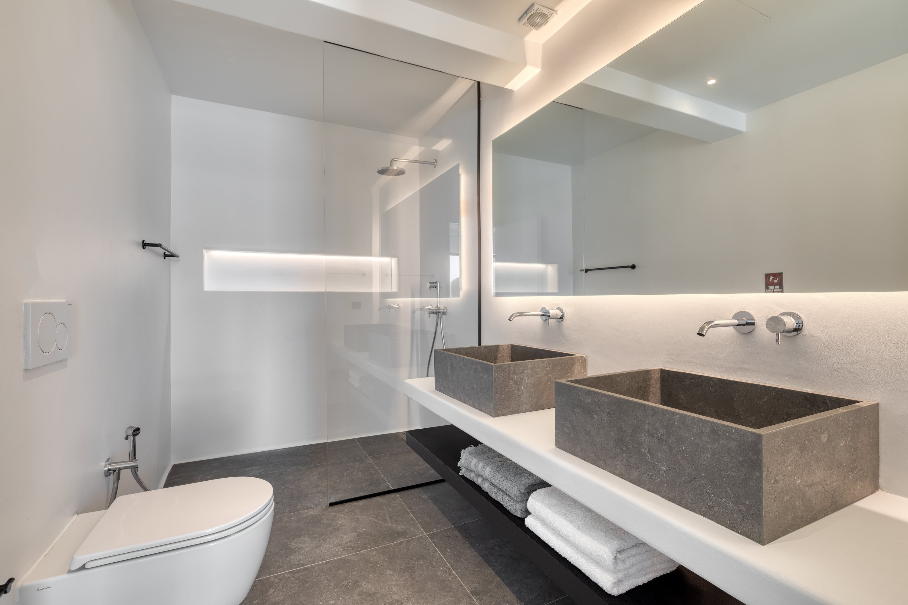 Modern bathroom with concrete sinks and a toilet.