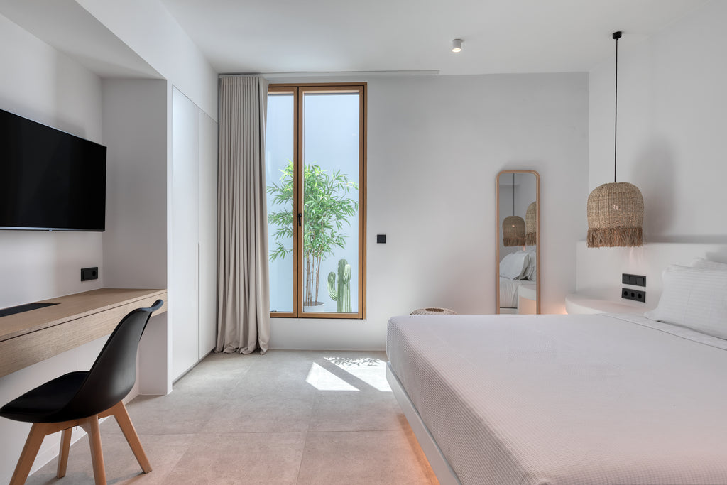 Modern bedroom with a bed, desk, and large window.