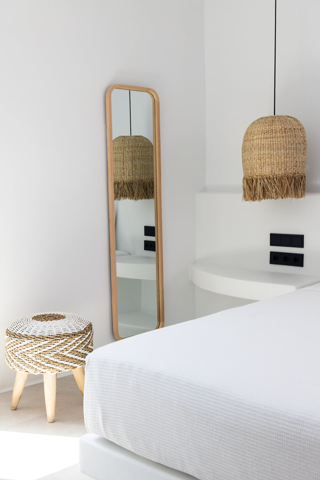 Modern bedroom with a bed, mirror, and decorative lamps.