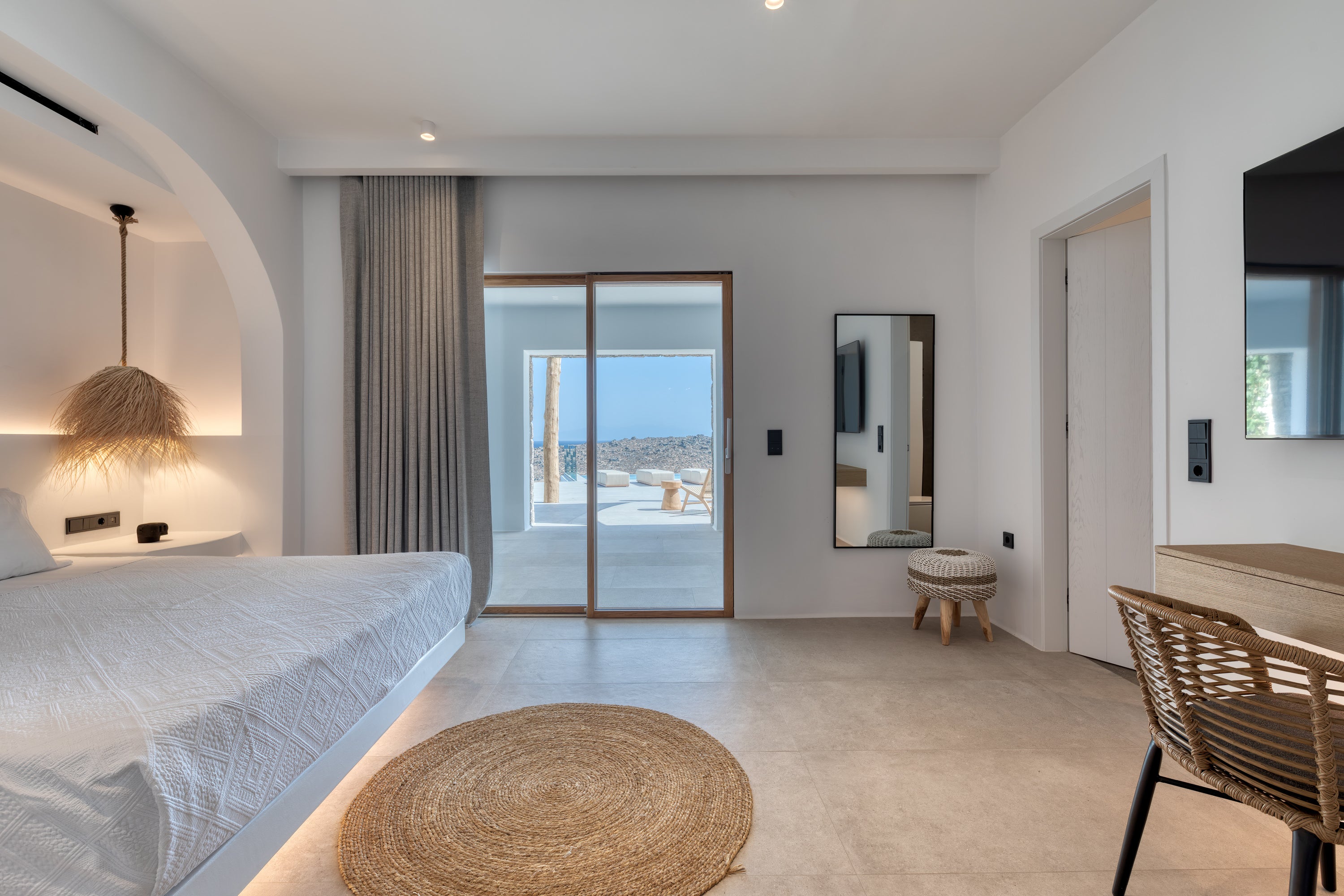 Modern bedroom with a bed, round rug, and sliding glass door leading to a patio.