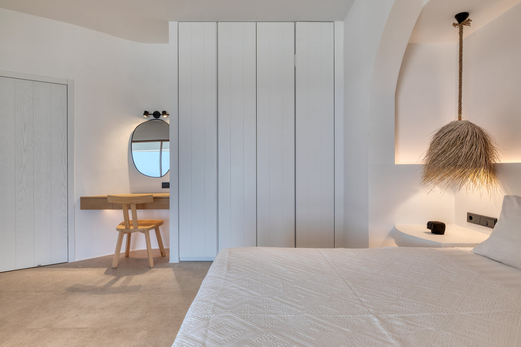 Modern bedroom with minimalistic design, bed, desk, and wall mirrors.