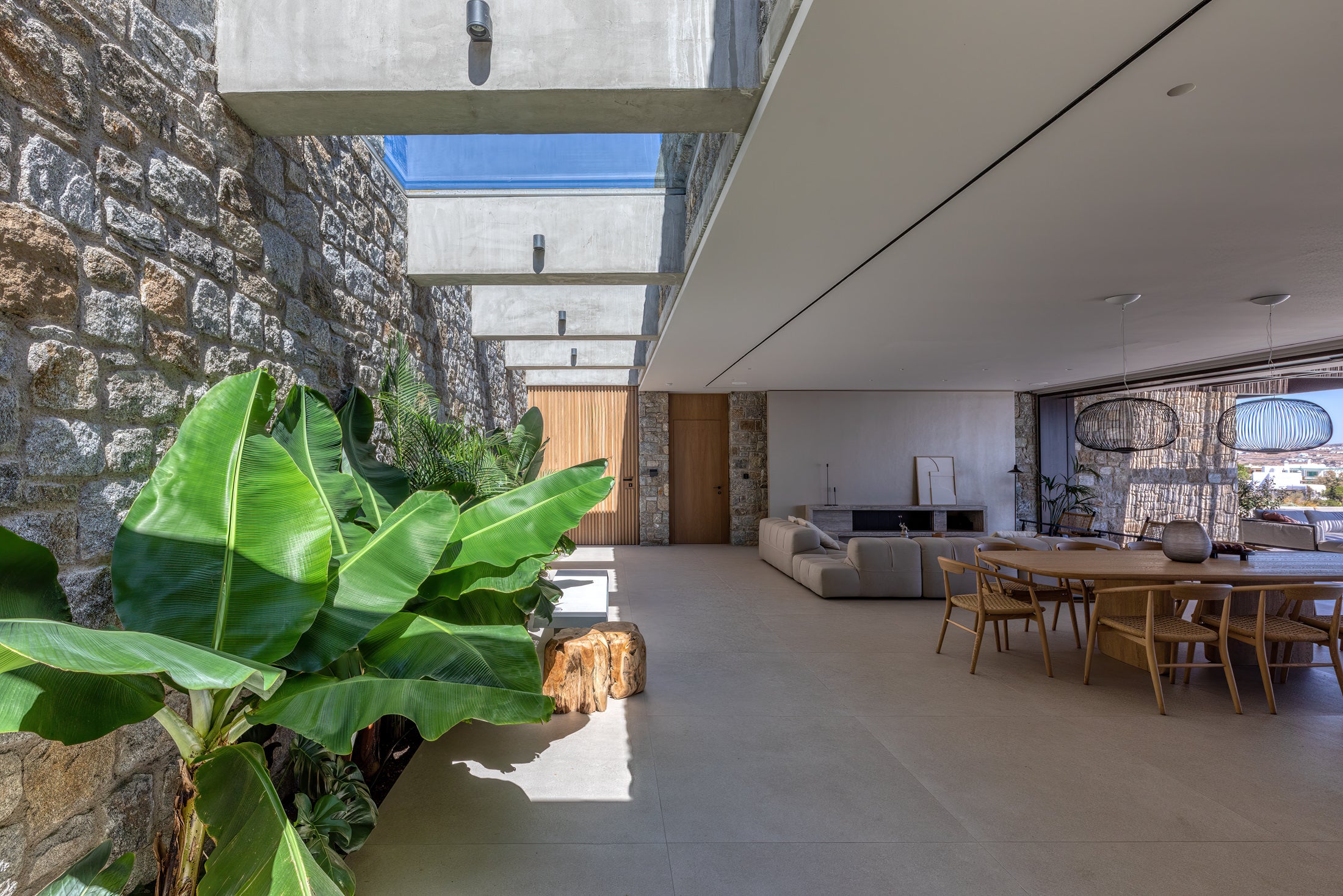 Modern interior with stone wall, glass ceiling, and furniture.