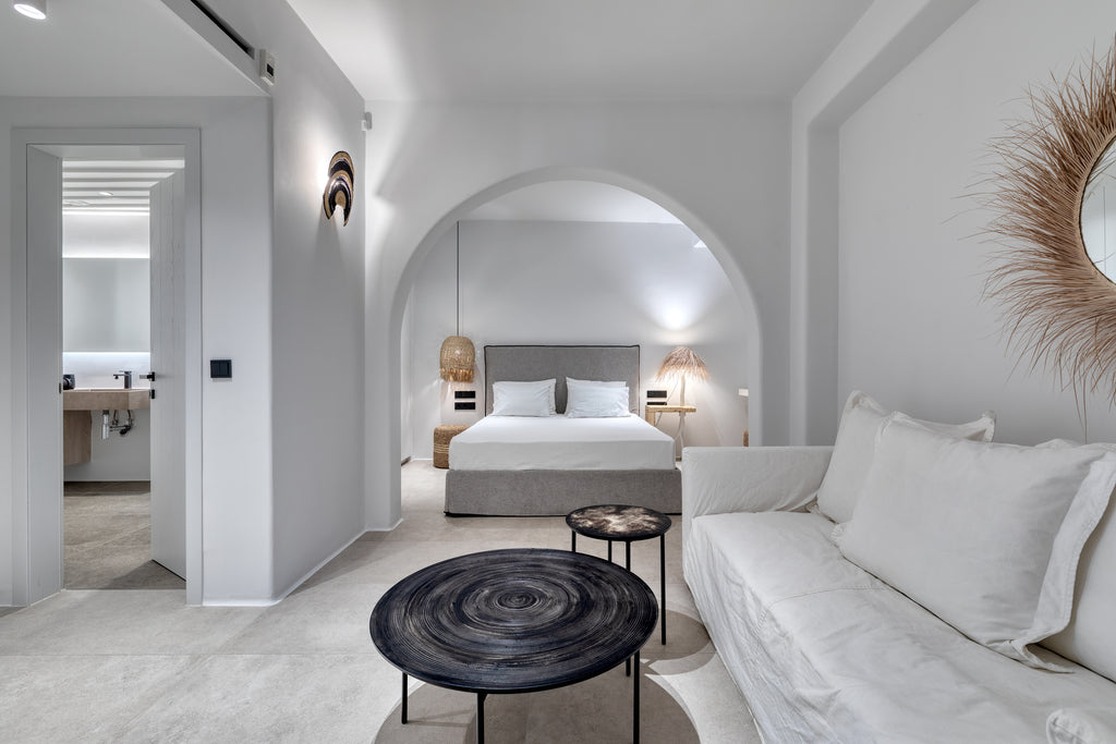 Modern bedroom with gray bed, white sofa, and decorative elements.