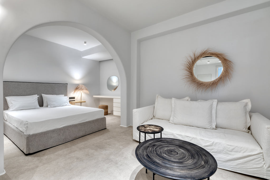 Modern bedroom with a bed, sofa, and decorative mirrors.