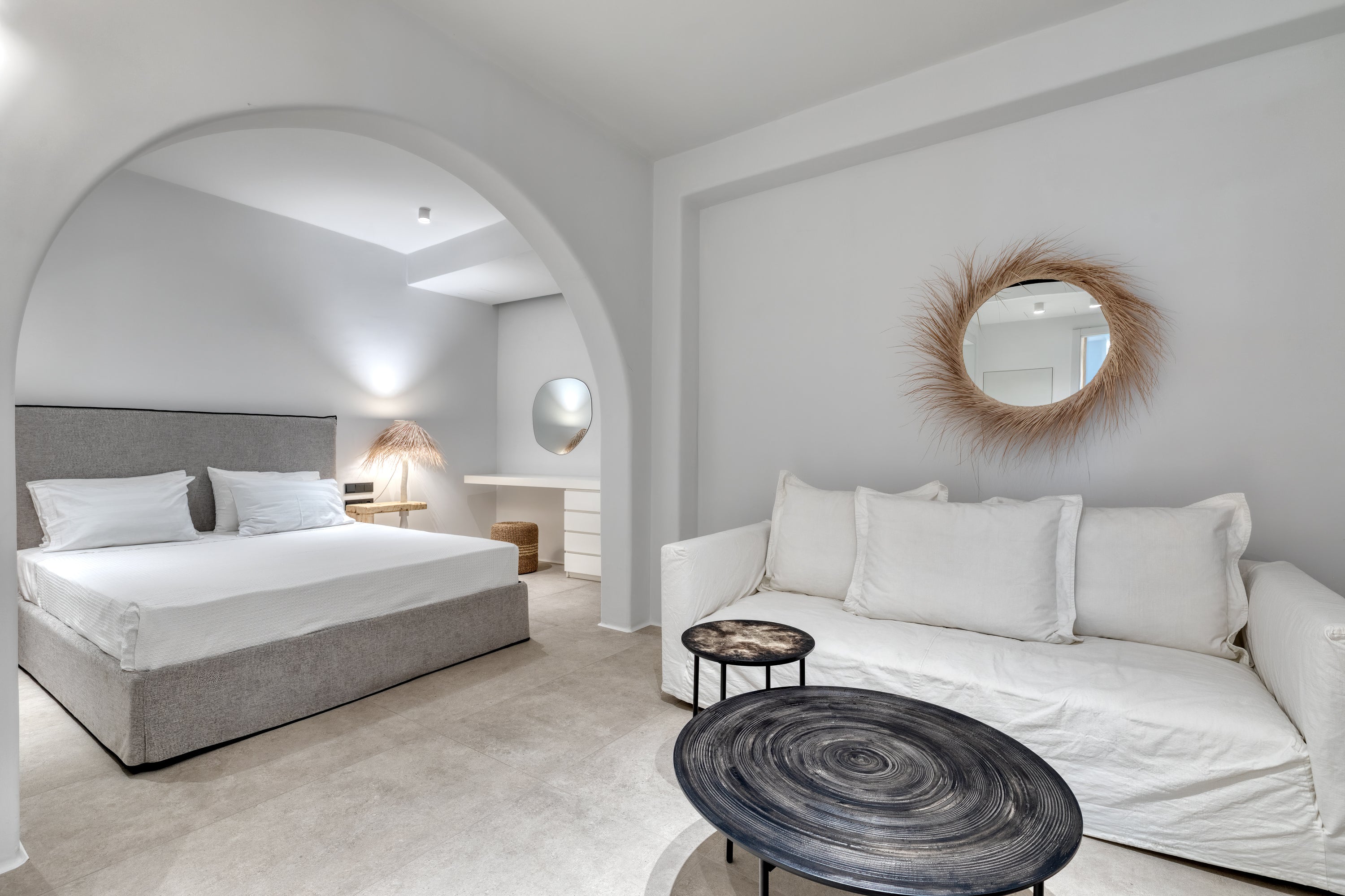 Modern bedroom with a bed, sofa, and decorative mirrors.