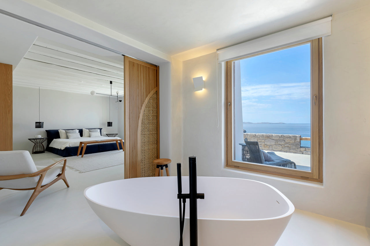 Modern bathroom with a large window overlooking the ocean.