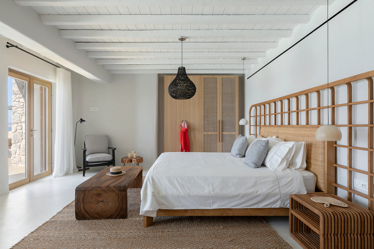 Modern bedroom with wooden bed, white bedding, and a view of the outdoors.