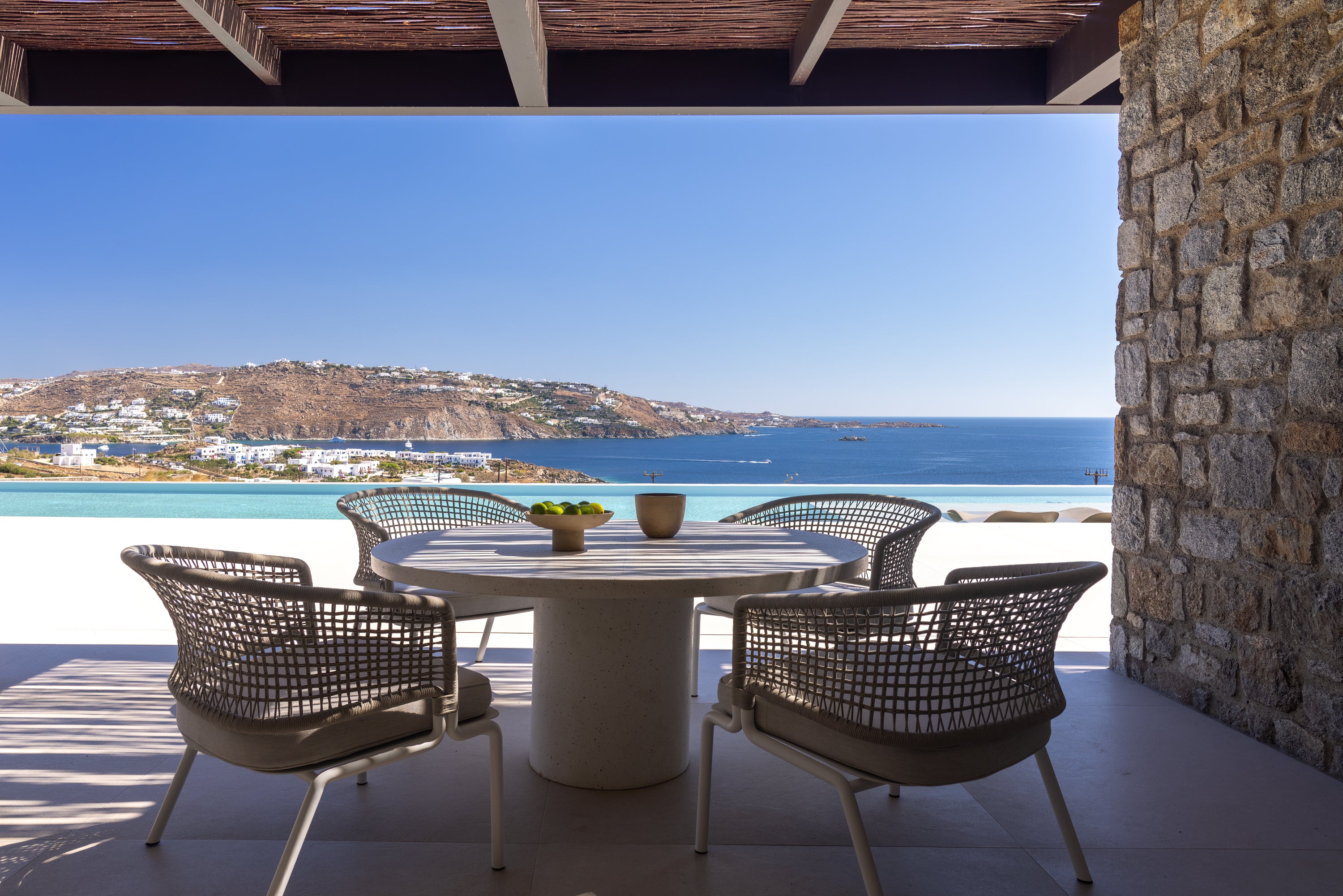 Outdoor dining area with a table and chairs overlooking a scenic ocean view.