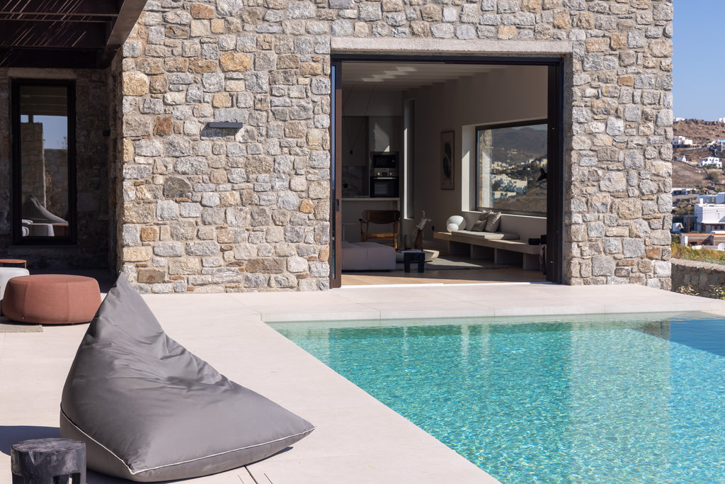 Modern outdoor setting with stone wall, pool, and patio furniture.