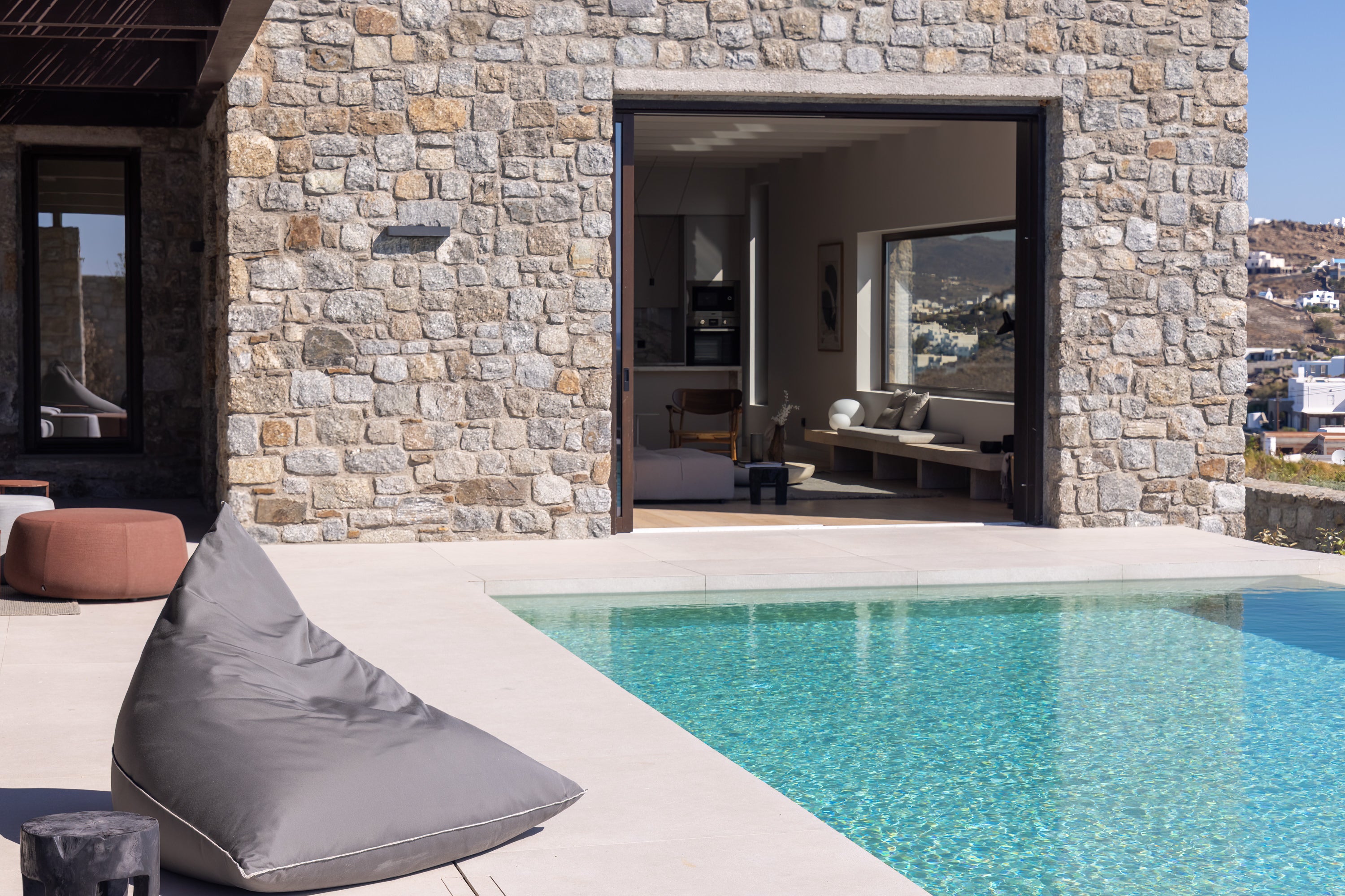 Modern outdoor setting with stone wall, pool, and patio furniture.