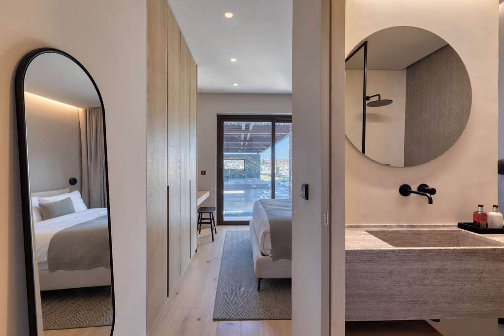 Modern bedroom and bathroom with mirrors and neutral decor.