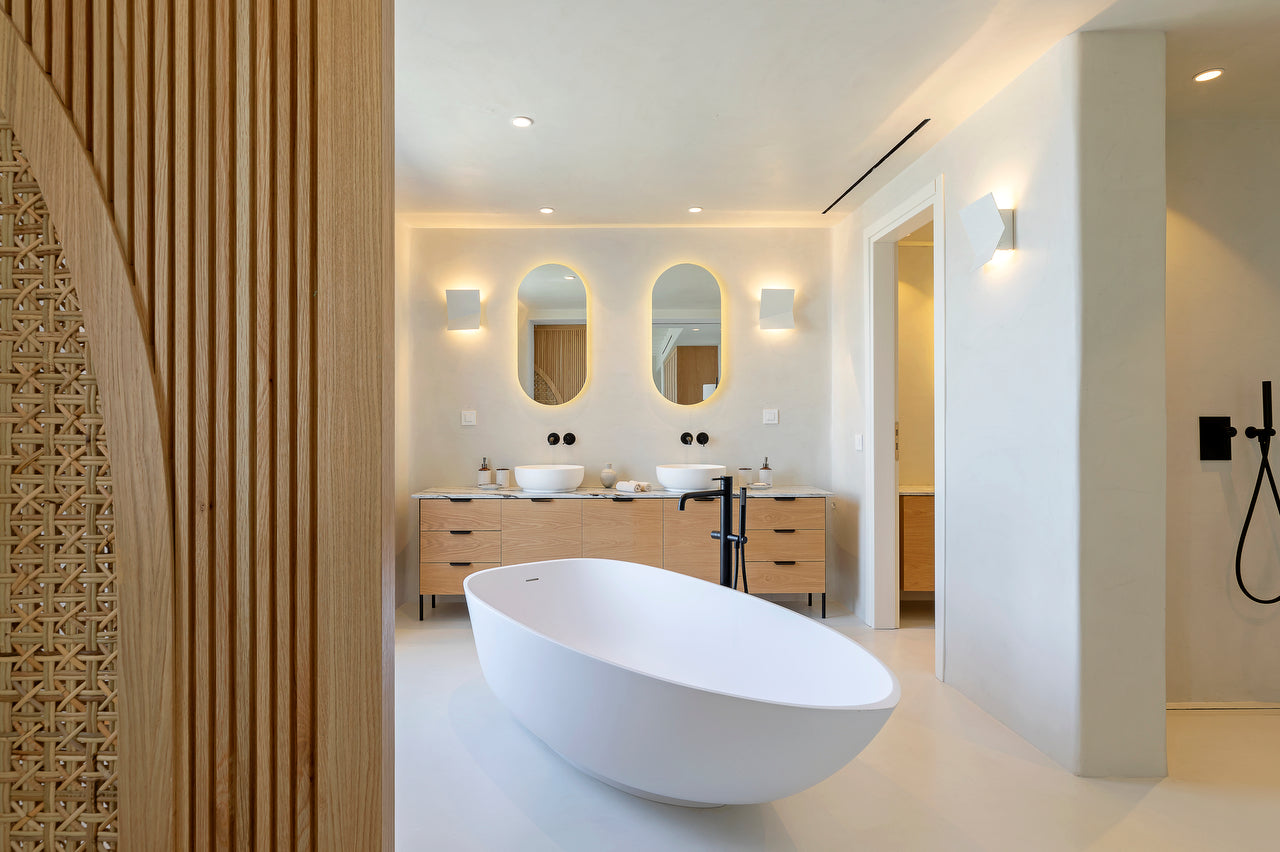 Modern bathroom with a freestanding bathtub, wooden vanity, and mirrors.