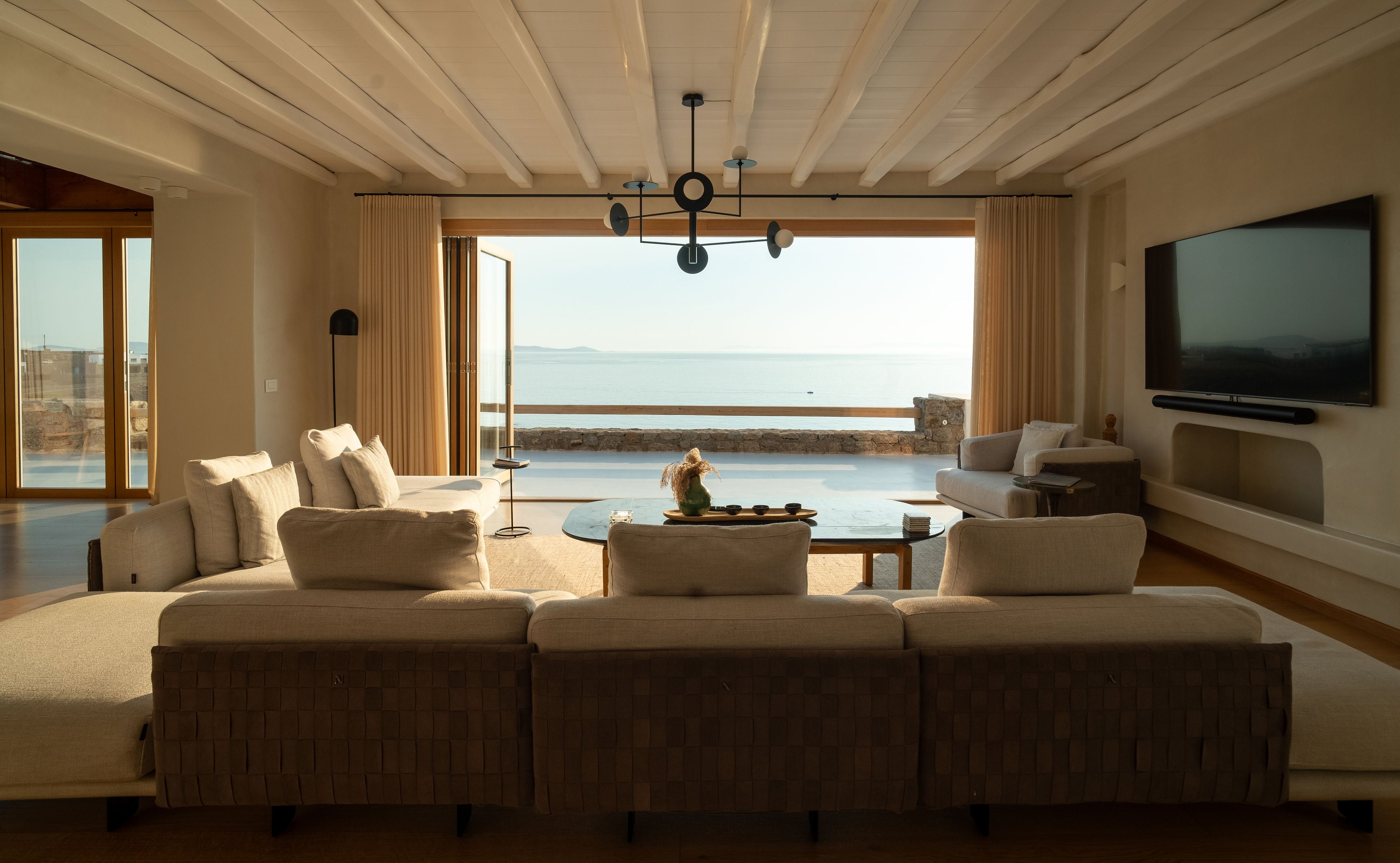 Modern living room with a large sofa, TV, and scenic view of water.