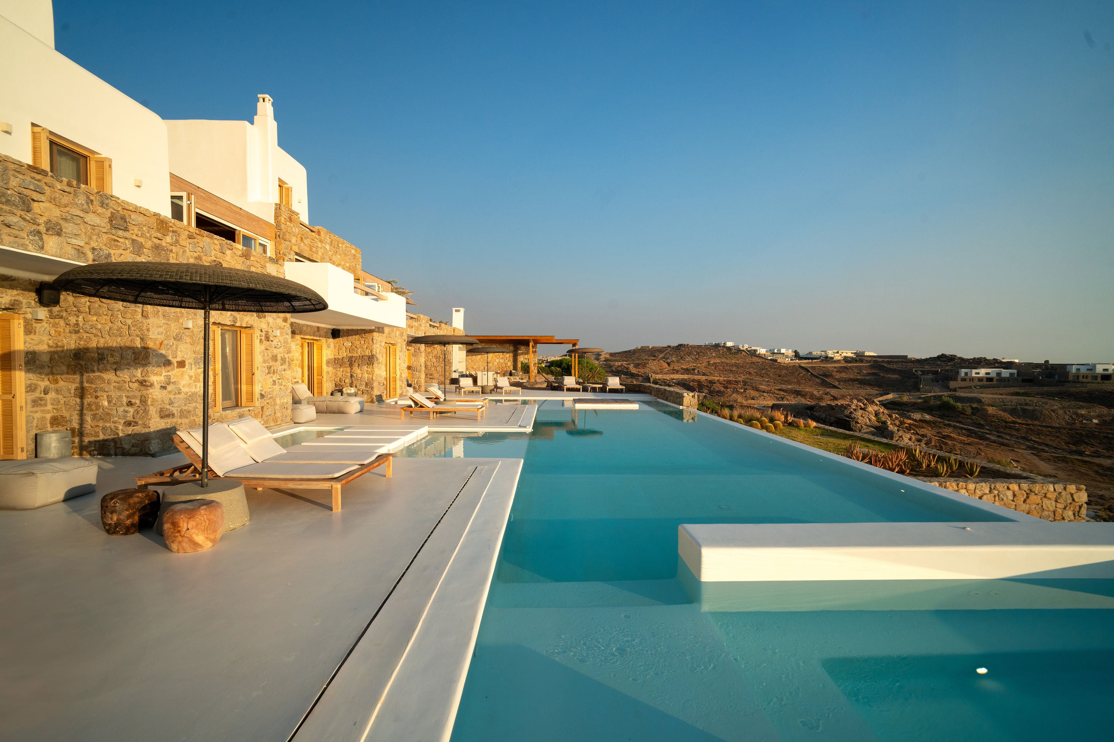 Luxury villa with a pool and outdoor seating area under a clear blue sky.