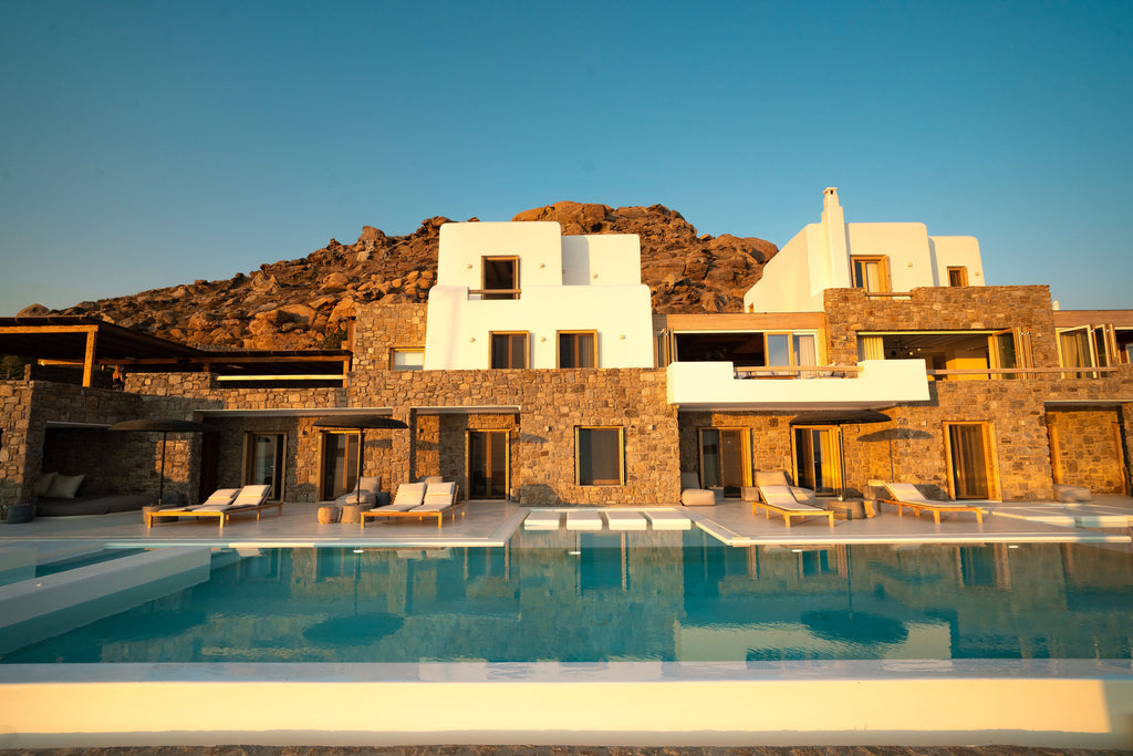 Luxury villa with pool and chairs against a mountainous background